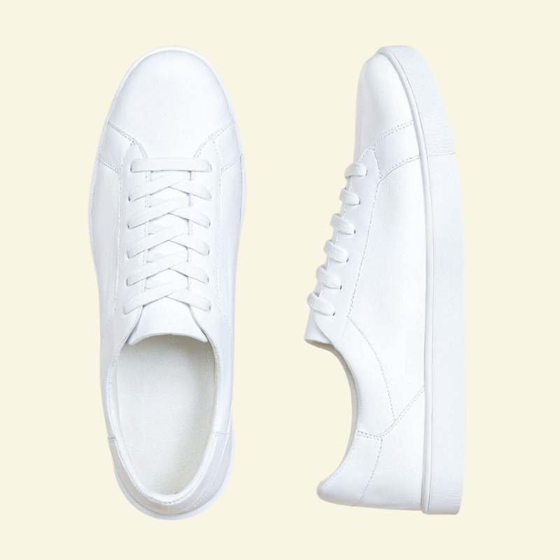 Białe niskie sneakersy męskie zaprezentowane z góry, widok na symetryczne ułożenie i czystą formę cholewki.
