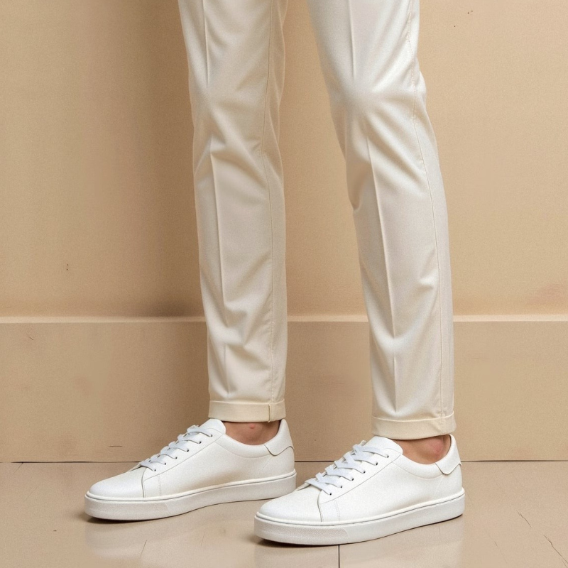 Białe niskie sneakersy męskie noszone przez modela, ujęcie na nogach w jasnej stylizacji o codziennym charakterze.