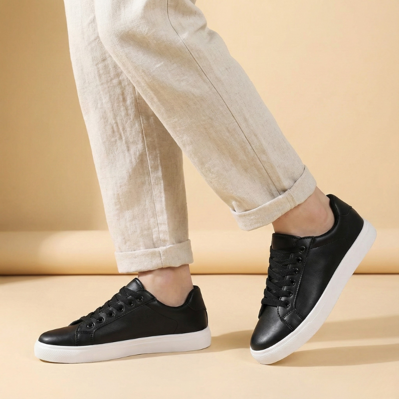 Niskie sneakersy męskie w wersji czarno-białej noszone przez modela, widok z boku, kontrastowa podeszwa widoczna w stylizacji casualowej.