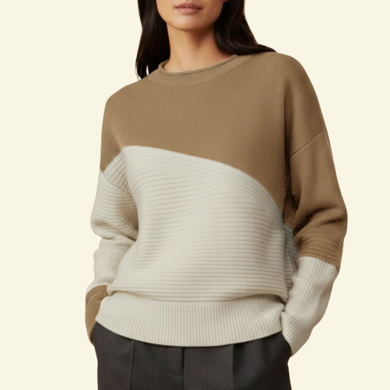 Modelka w swetrze color-block w odcieniu beżowym z jasnokremowym dołem; luźny, miękki fason.