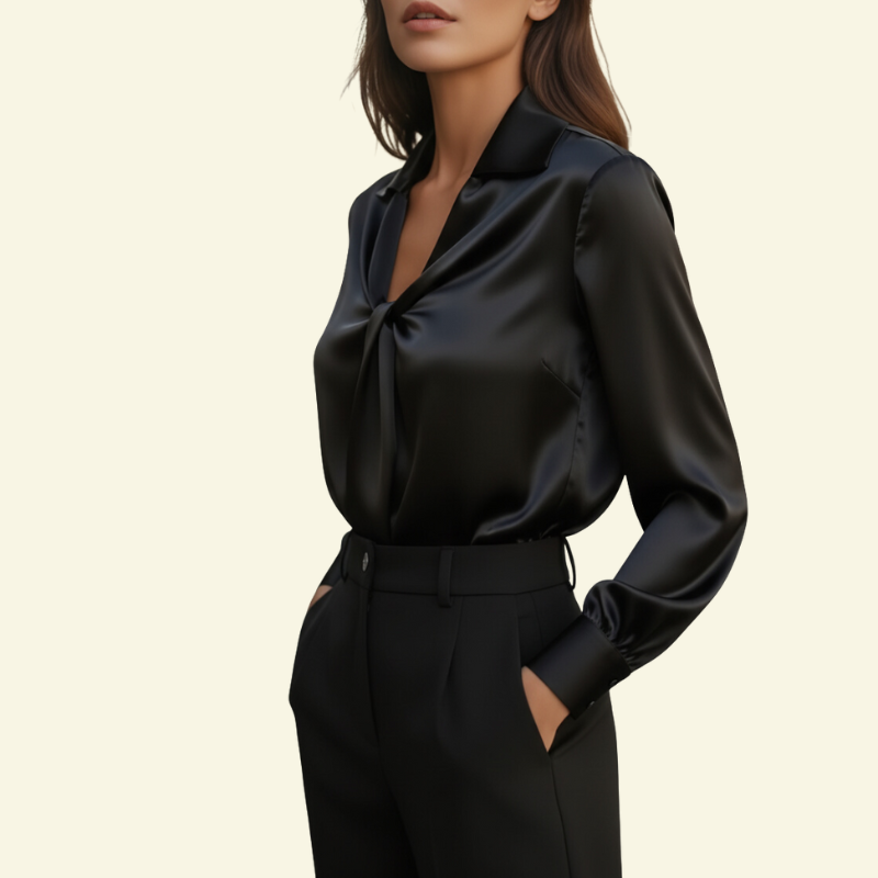 Modelka w czarnej bluzce ze skręceniem z przodu i kołnierzem open-collar; gładka tkanina podkreśla wyrazisty, klasyczny efekt.