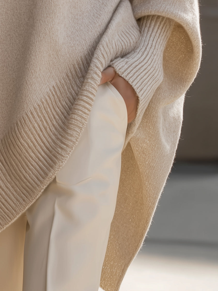 Beżowy sweter oversize damski widziany z boku, z prążkowanym mankietem i wydłużonym bokiem — Lubomirske
